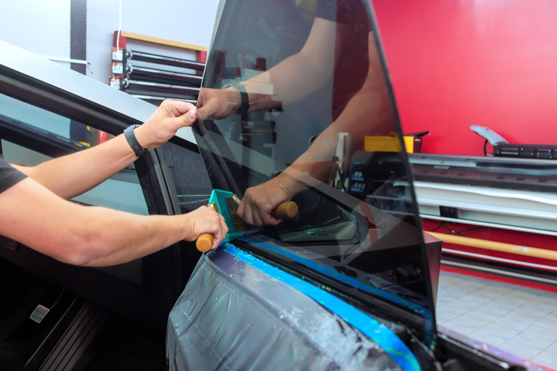 Window tinting process being performed on a car in a workshop setting